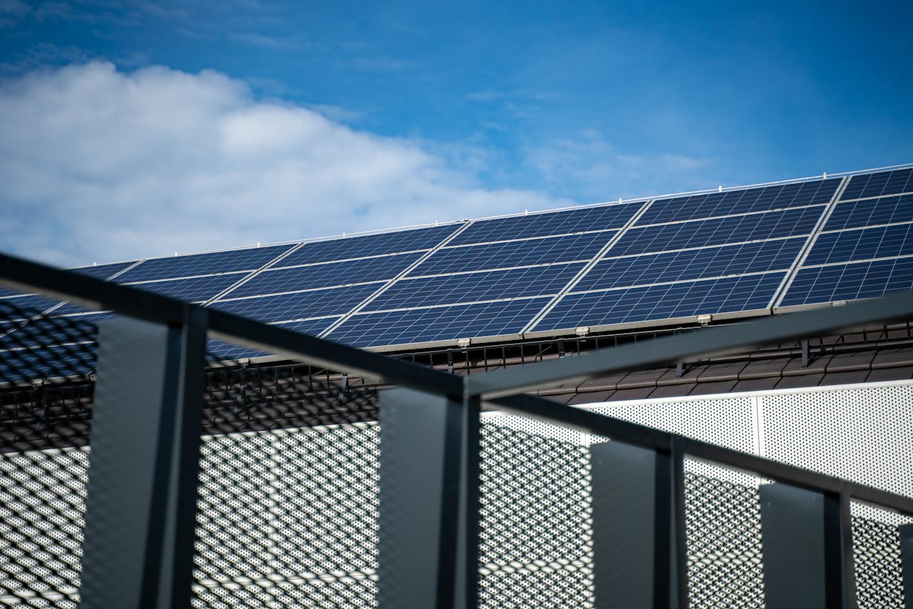 Services Close-up view of modern solar panels on a rooftop against a clear blue sky, representing clean energy.