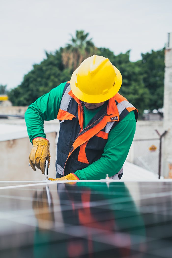 About Professional solar panel technician working outdoors with PPE.